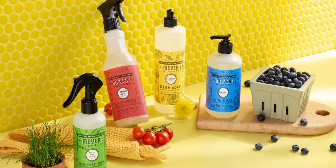 A bottle of Mrs. Meyer’s Clean Day dish soap with dandelion scent, featuring a yellow label with dandelion illustrations. The bottle has a black flip-top cap.