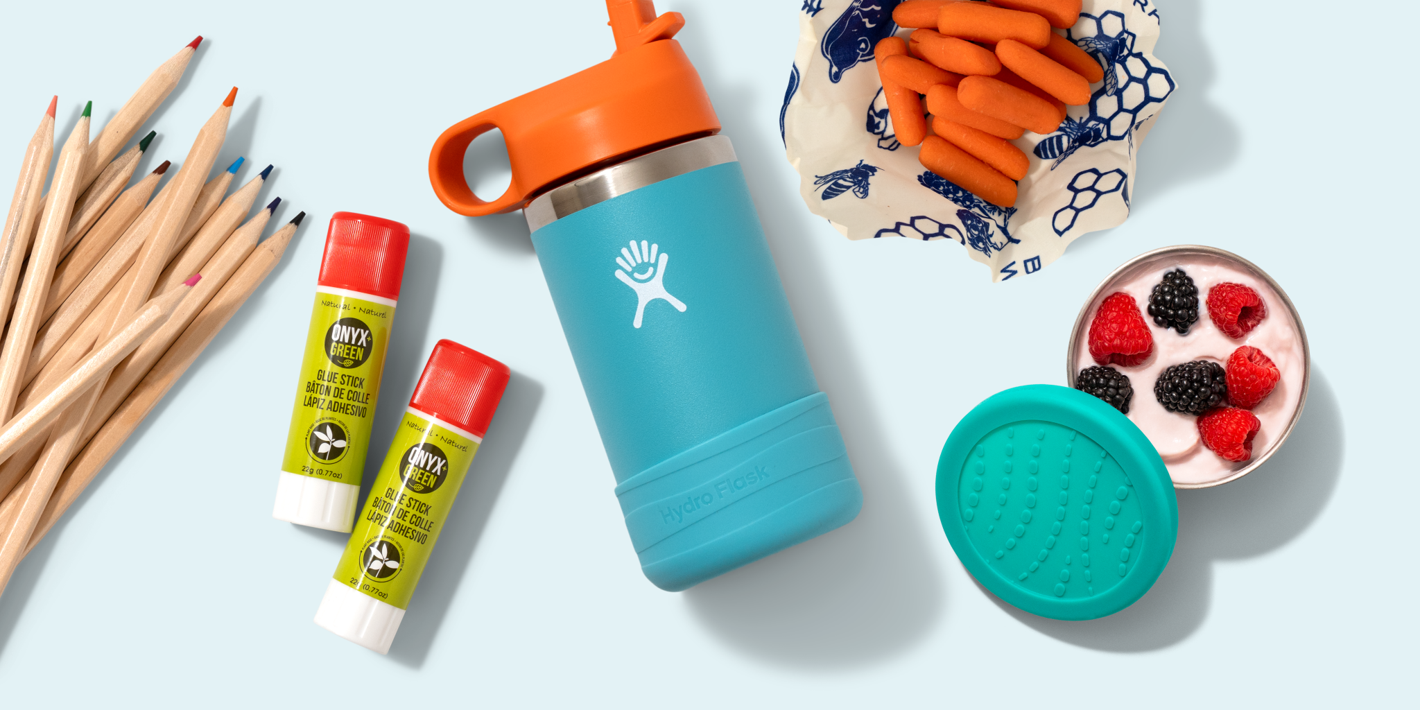 A collection of eco-friendly cleaning products, including toilet paper rolls, spray bottles, cleaning cloths, a blue bottle, and two small liquid bottles, displayed on a light green background.