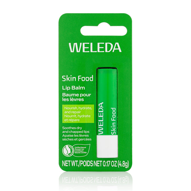 A green package of Weleda Skin Food Lip Balm contains a green and white tube. The packaging highlights nourishing and soothing benefits for dry, chapped lips.