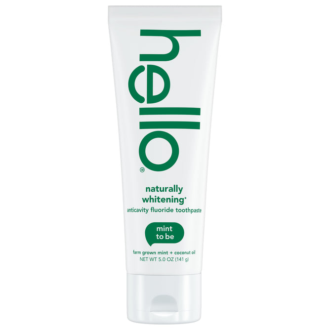 A white tube of hello Naturally Healthy Whitening Fluoride Toothpaste with green text, displaying “mint to be” and “farm grown mint + coconut oil”—ideal for those seeking a natural whitening toothpaste.