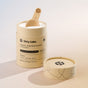 An open cylindrical container of Dirty Labs Probiotic Toilet Bowl Cleaner with Phytolase® reveals a wooden scoop resting in white powder. The beige container features black text and minimalist graphics, emphasizing its use of Phytolase® bioenzyme technology for an effective deep-cleaning toilet bowl experience.