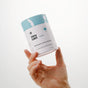 A hand holds a container of Dirty Labs Bio Enzyme Laundry Booster against a plain white background. The label, designed in blue and white, displays the product name and brand, emphasizing its advanced enzyme technology formulated to tackle biological stains.
