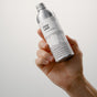 A hand holds a metallic bottle labeled "Dirty Labs Bio Laundry Detergent with Phytolase® - Free & Clear" against a plain, light background, emphasizing its reputation as a laundry detergent suitable for sensitive skin.