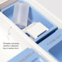 A clear plastic beaker rests in the blue compartment of a washing machine dispenser tray, with instructions to fill the beaker with Dirty Labs Bio Laundry Detergent with Phytolase® – Jasmine, Matcha, Vetiver, then place it directly in the dispenser tray or washer drum.