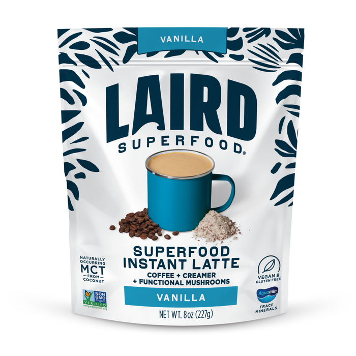A package of Laird Superfood Vanilla Instant Latte, a vegan, gluten-free superfood coffee featuring functional mushroom benefits, shown with a blue mug, coffee beans, and powder.