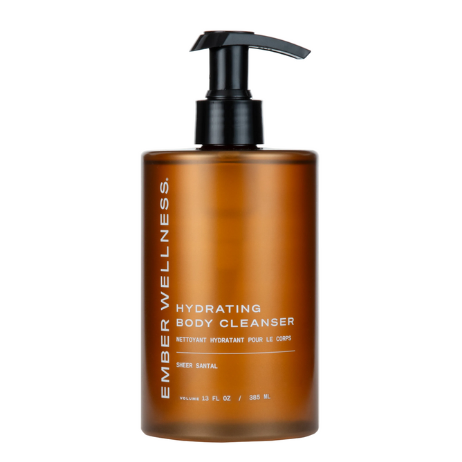 An amber bottle with a black pump labeled "Ember Wellness Hydrating Body Cleanser" in white text, featuring the Sheer Santal scent. This oil-to-milk cleanser hydrates the skin and supports the skin’s microbiome, with each bottle containing 13 fl oz (385 mL).