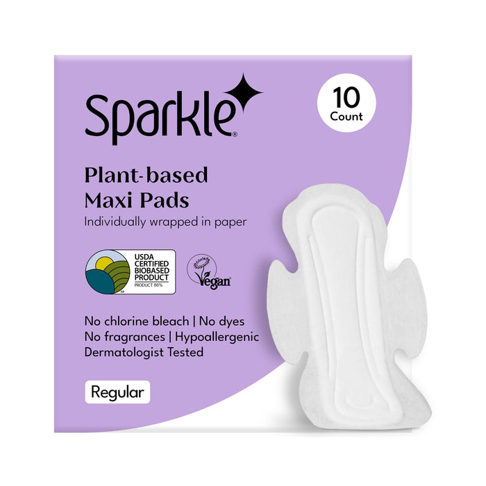 A purple and white box of Sparkle Maxi Pads, With Wings is shown with one hypoallergenic pad outside. The box features USDA biobased, vegan, and dermatologically tested labels. Contains 10 regular pads.