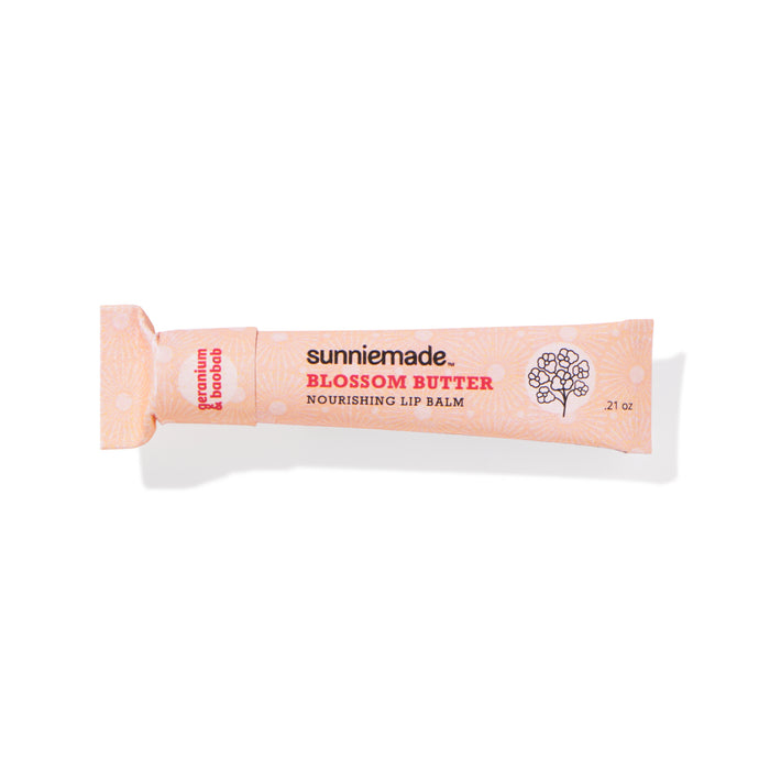 A pink paper squeeze tube labeled Sunniemade Nourishing Lip Balm - Blossom Butter, featuring a floral design and white polka dots, is shown on a white background.
