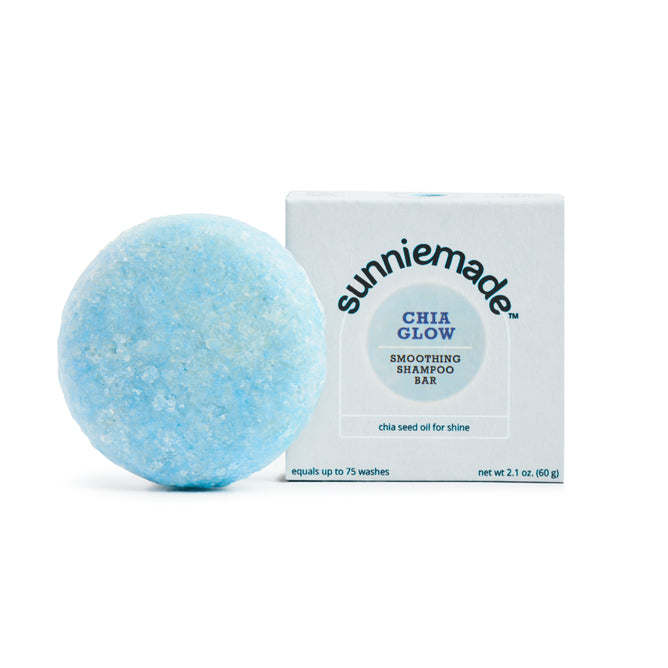 A round, light blue Smoothing Shampoo Bar - Chia Glow from Sunniemade sits beside its box packaging. Infused with chia seed oil for shine, this plastic-free shampoo bar is formulated to reduce frizz and leave your hair looking healthy and radiant.