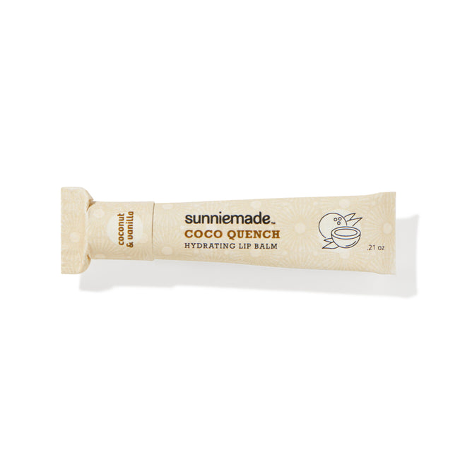 A beige tube of Sunniemade Hydrating Lip Balm – Coco Quench, infused with coconut and vanilla flavor, features minimalist line drawings of a bird and a coconut on the tube’s right side. Made with nourishing cocoa butter and packaged in recyclable materials, this lip balm offers both hydration and an eco-friendly choice.
