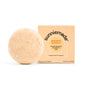 A round, beige shampoo bar rests beside a light orange, square box labeled Sunniemade Moisturizing Shampoo Bar - Mighty Mango, featuring hydrating mango butter for moisture.