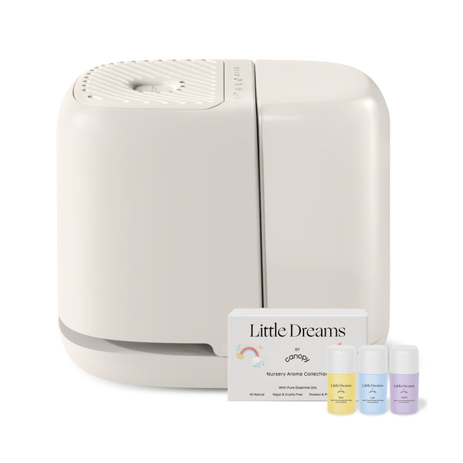 A sleek, white Canopy Nursery Humidifier sits beside a Little Dreams Nursery Aroma Collection box and three small bottles of pediatrician-recommended essential oils in yellow, blue, and purple.