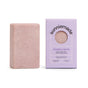 A pink rectangular bar of soap rests next to a lavender box labeled Sunniemade Exfoliating Body Bar Soap - Purple Rain. Made with natural body care in mind, this luxurious bar is infused with lavender and lavandin essential oils, exfoliating oatmeal, and Brazilian purple clay, providing a gentle yet effective cleanse.