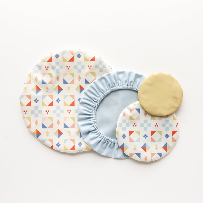 Four Esembly Baby Reusable Bowl Covers made from upcycled materials are displayed on a white background in assorted sizes and patterns—ideal for eco-friendly food storage.