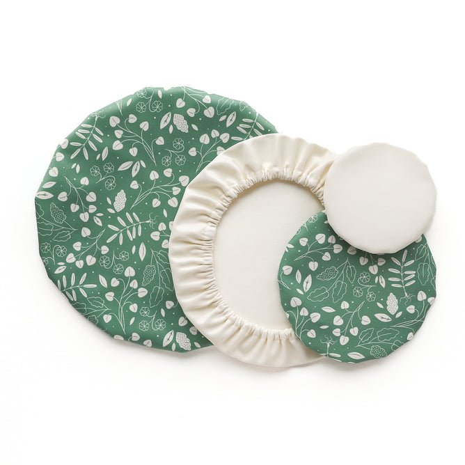 Esembly Baby’s Reusable Bowl Covers made from Upcycled Materials come in a 4-pack with green leaf-and-berry prints and plain white options. These machine-washable, sustainable covers are shown arranged on a white background.