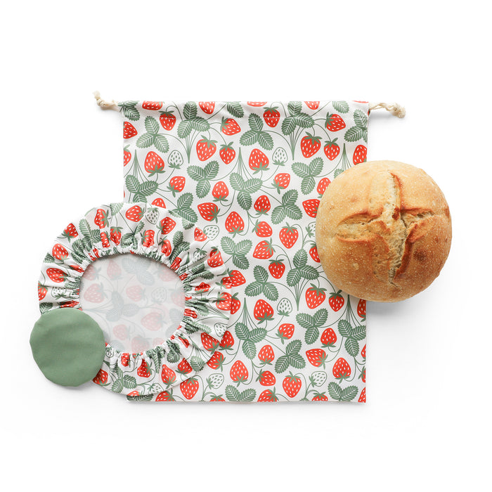 The Sourdough Proofing Kit by Esembly Baby includes a round sourdough loaf, a reusable fabric bread bag and bowl cover with a red strawberry and green leaf pattern, plus a small green circular cloth.
