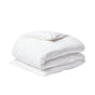 A neatly folded Coyuchi Organic Crinkled Percale™ Duvet Cover in white, topped with a matching pillow, both made from breathable crinkled percale bedding, set against a plain white background.