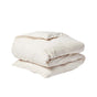 A neatly folded, light beige comforter or duvet—featuring the Coyuchi Organic Crinkled Percale™ Duvet Cover—is placed on a plain white background.