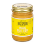A glass jar of Big Spoon Roasters Banana Flax Wag Butter, a nutritious peanut butter for dogs, with a yellow label and gold lid.