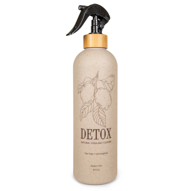 A beige spray bottle labeled “Yoga Mat Cleaner 16oz” by Yoloha Yoga features a lemon illustration, black trigger spray top, bamboo accent, and text highlighting tea tree and lemongrass scents. Made with organic essential oils, this mat spray is perfect for keeping cork yoga mats fresh and naturally clean.