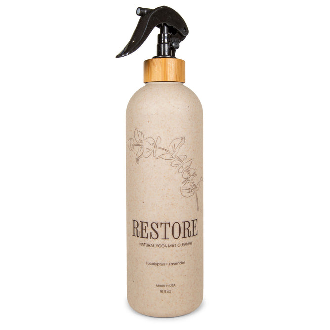 A beige spray bottle labeled Yoloha Yoga Mat Cleaner 16oz with eucalyptus and lavender scents. This organic essential oil spray features a bamboo top, a black sprayer, and a simple floral design—perfect as a mat cleaning spray, even for cork yoga mats.