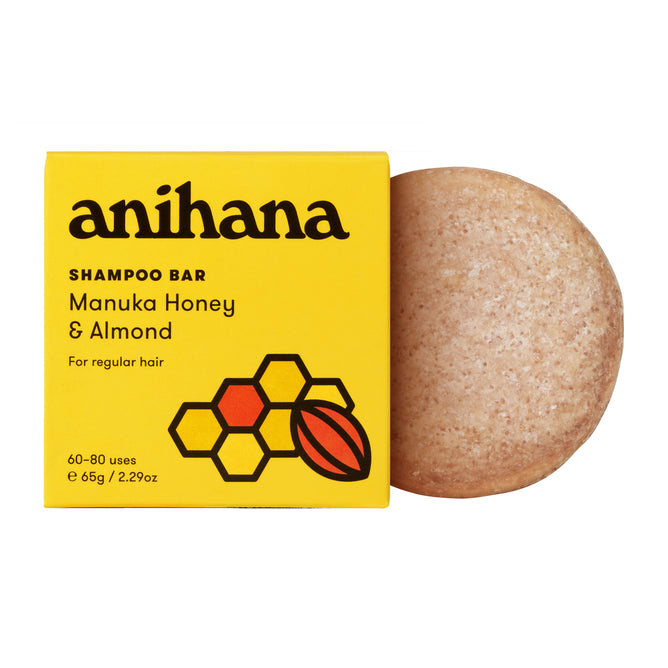 A yellow Anihana Shampoo Bar (Regular Hair) box with honeycomb and almond designs sits beside a round, beige mānuka honey shampoo bar.