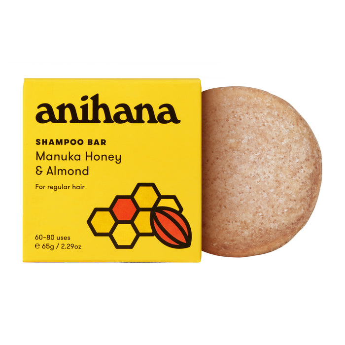 A yellow Anihana Shampoo Bar (Regular Hair) box with honeycomb and almond designs sits beside a round, beige mānuka honey shampoo bar.