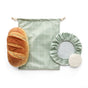 The Sourdough Proofing Kit by Esembly Baby features a sourdough loaf paired with a green grid-patterned bread bag, a green elastic food cover, and a round white item on a crisp white background.