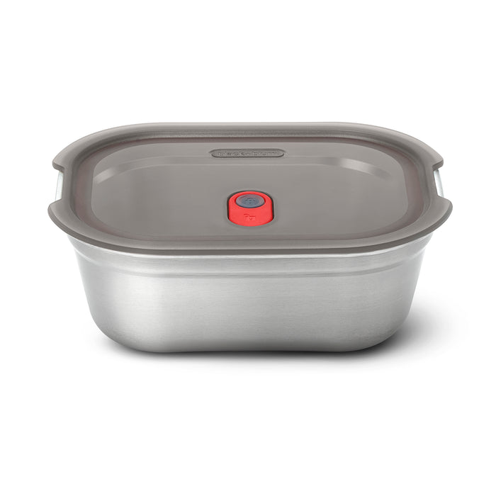 The Black + Blum Steel Food Box is a rectangular, microwaveable stainless steel container with a gray plastic lid featuring a red center button that fits securely and is leakproof.