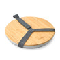 The Black + Blum Steel Plate Set of 4 features a round bamboo lid that doubles as a chopping board, secured by a gray carry strap. The lid has a subtle engraved logo in the corner.
