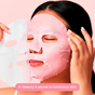 A woman applies the FaceTory Girls’ Night Glow Face Sheet Mask against a soft pink background. Text at the bottom reads, “K-Beauty’s secret to hydration and brightness.”.