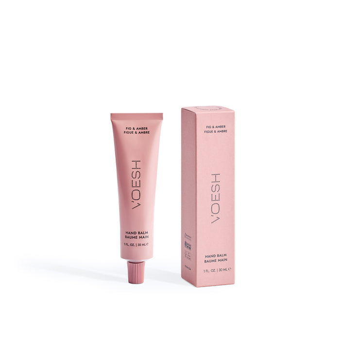 A pink tube of VOESH Hand Balm stands upright beside its matching box, both labeled in elegant lettering—perfect as a travel-size hand cream for deep moisture on the go.