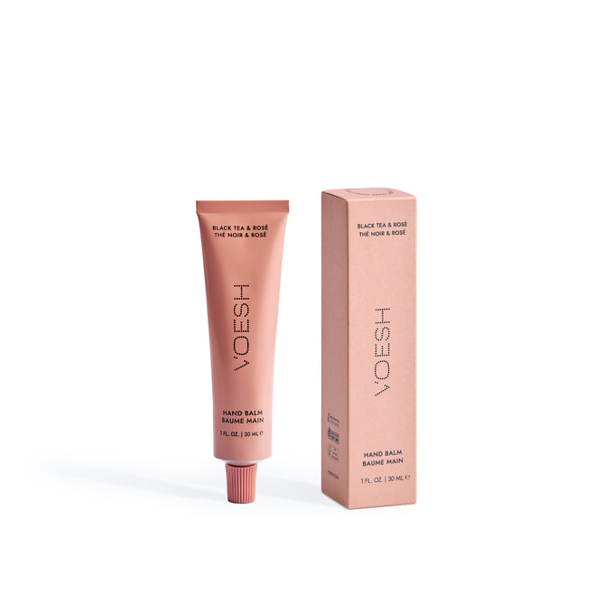 A pink VOESH Hand Balm tube stands upright beside its matching box on a white background. Both feature minimalist lettering, making this travel-size hand cream ideal for deep moisture on the go.