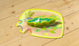 A wooden crocodile figure sits on a puzzle-shaped card depicting a pond as part of the My Very First Games - Let’s Be Veterinarians, 2+ Years educational board game.