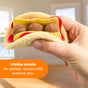 A hand holds a plush taco from the Creative Play Food Meal Kit- Fresh Box, 3+ Years, featuring three meatballs nestled between layers of fabric representing sauce and cheese.