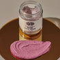 A jar of Anima Mundi ROSE Face Mask, Detoxify + Hydrate, filled with pink powder, rests on a gold surface. In front, its creamy pink paste promises a hydrating botanical clay mask experience.