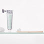 A tube of Davids toothpaste stands upright next to a Davids Premium Bamboo Toothbrush - Adult Soft, featuring soft bristles with toothpaste applied, both resting on a glass shelf against a white background.