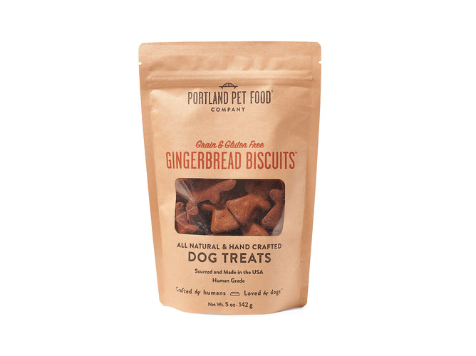 A brown package of Portland Pet Food Companys Grain & Gluten-Free Dog Biscuits highlights their all-natural quality. Handcrafted with Pacific Northwest ingredients and Bobs Red Mill Flour, these 5 oz human-grade treats, resembling gingerbread and free from grains and gluten, are visible through a clear window.