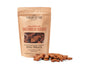 A brown paper package labeled Portland Pet Food Companys Grain & Gluten-Free Dog Biscuits made with 100% whole food, human-grade ingredients. These bone-shaped biscuits, crafted with Pacific Northwest ingredients and Bobs Red Mill Flour, are scattered about, proudly stating Made by humans, loved by dogs.