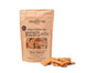 A brown paper bag of Portland Pet Food Company Grain & Gluten-Free Dog Biscuits sits next to bone-shaped treats. Made with Pacific Northwest ingredients, these apple and mint-flavored snacks are crafted with 100% whole food, human-grade ingredients for your furry friends enjoyment.