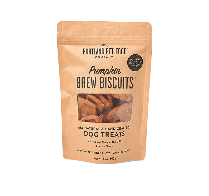 Portland Pet Food Companys Upcycled Dog Brew Biscuits come in a brown paper bag with a clear window, highlighting their all-natural and human-grade ingredients, sourced in the USA using spent grains.