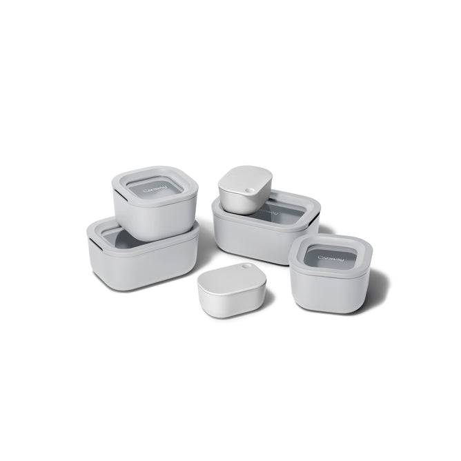 The Caraway Mini Food Storage Set W/ Storage features six white, non-toxic containers with matching lids, perfect for kitchen organization. Rectangular and oval containers are stackable and nest together for easy storage.