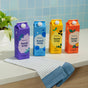 Four colorful cartons of Grove Co. Hand Soap – Hydrates & Moisturizes With Every Wash sit on a countertop with a striped cloth and potted plant, featuring recyclable packaging against a blue tiled wall.