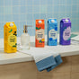 Four colorful cartons of Grove Co. Hand Soap – Hydrates & Moisturizes With Every Wash are lined up on a countertop by a glass soap dispenser. A striped towel lies nearby, with the recyclable packaging set against a tiled wall.