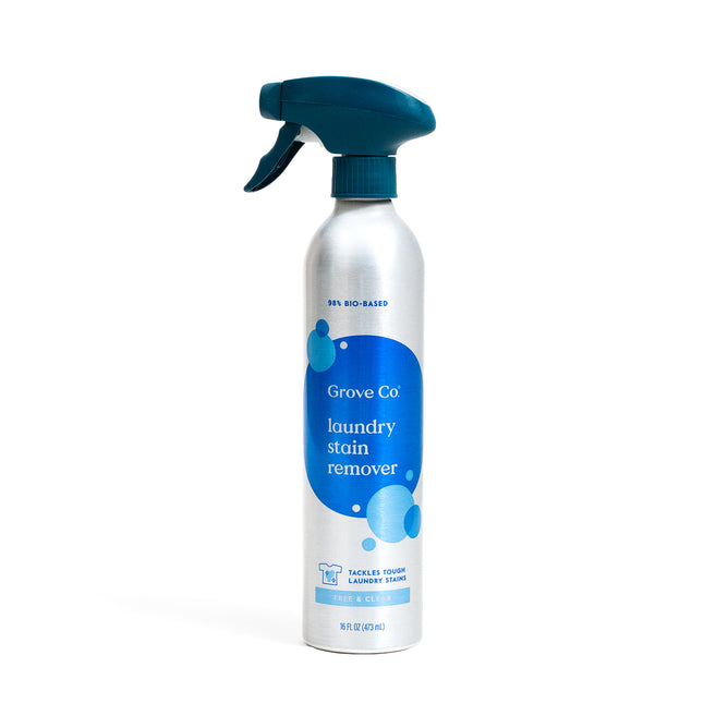 A silver spray bottle labeled Grove Co. Laundry Stain Remover — Made with Powerful Stain-Fighting Enzymes, featuring a blue trigger and label, stands upright on a white background.