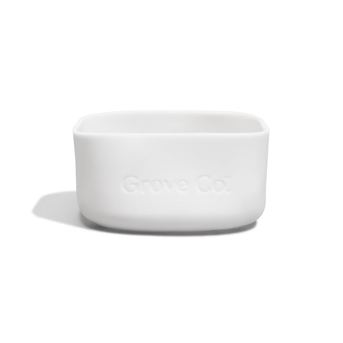A small, white, rectangular Grove Co. Silicone Sleeve - Glass Foaming Hand Soap Dispenser with rounded edges, featuring a non-slip silicone sleeve and Grove Co. embossed on the front, displayed against a plain white background.