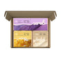 Open cardboard box containing the Soapymania Body Care Set: purple sugar scrub cubes, an orange exfoliating bar soap, and a beige loofah, each with bold white labels and close-up ingredient images.
