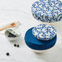 Esembly Baby’s Reusable Bowl Covers made from Upcycled Materials (4-Pack)—three in blue prints and solids—are arranged on marble with a bowl of blueberries, spoon, and napkin for a sustainable kitchen storage scene.