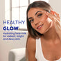 A smiling woman with glowing skin touches her face indoors, wearing a white tank top. Text: HEALTHY GLOW. FaceTory Glow Serum Face Milk hydrates for radiant, bright, dewy skin with a glass-skin finish.