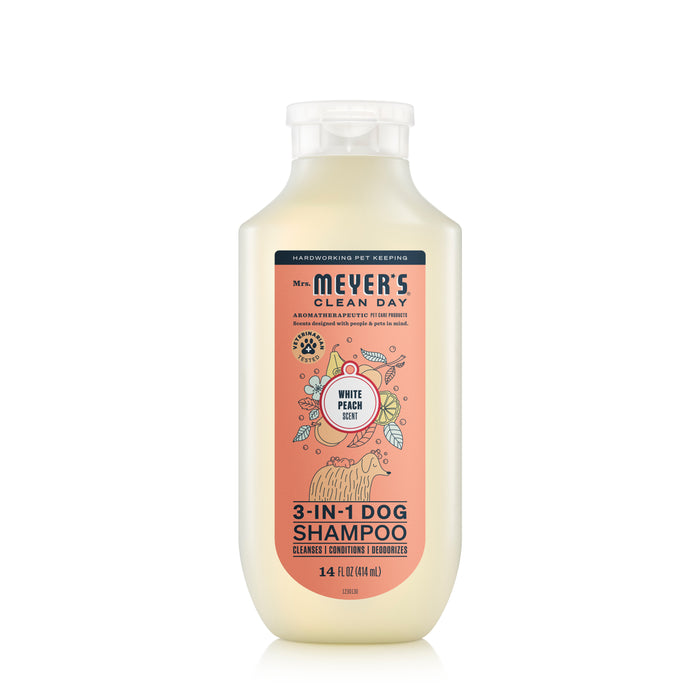 A 14 fl oz (414 ml) white bottle of Mrs. Meyers 3-in-1 Dog Shampoo is pH balanced, veterinarian tested, and features a white peach scent. The label has playful dog and peach illustrations, highlighting cleansing, conditioning, and moisturizing properties for your pets safety.